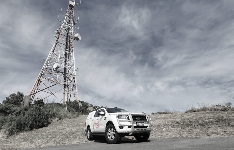 a Vital branded vehicle next to a radio tower.