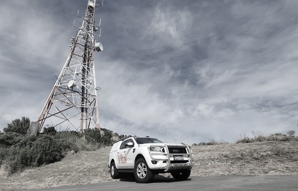 a Vital branded vehicle next to a radio tower.